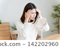 A woman checks her hairline in the mirror. 142202960