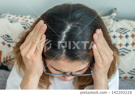 High angle view of Asian showing her forehead with part of her thin hair, she had hair loss problem. Female pattern hair loss can progress from a widening part to overall thinning. 142203228