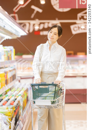 A young woman is selecting items while pushing a shopping cart in the refrigerated food section of a supermarket. A young woman is selecting items while pushing a shopping cart in the refrigerated food section of a supermarket. 142203340