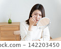 A woman looking in the mirror due to eye problems. 142203450