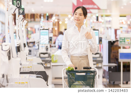 A female customer paying at a supermarket's self-checkout counter. 142203483
