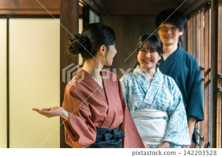 A couple in yukata (traditional Japanese summer kimono) serving guests at a long-established hot spring inn, luxury inn, or temple lodging. A couple in yukata (traditional Japanese summer kimono) serving guests at a long-established hot spring inn, luxury inn, or temple lodging. 142203528
