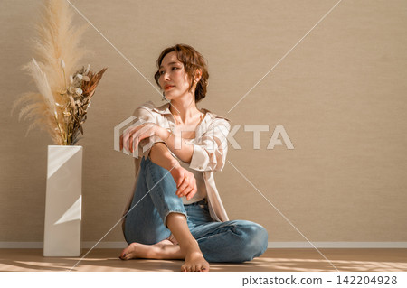 A female model wearing denim jeans in a brightly lit room A female model wearing denim jeans in a brightly lit room 142204928