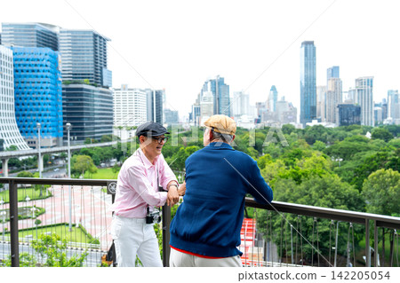 Two senior LGBTQ men share warm handshake on urban balcony overlooking lush green park and city skyline Two senior LGBTQ men share warm handshake on urban balcony overlooking lush green park and city skyline 142205054