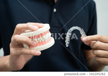 Man holding invisible aligner orthodontic retainer for dental teeth straightening. Man holding invisible aligner orthodontic retainer for dental teeth straightening. 142205262