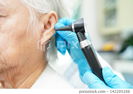 Otolaryngologist or ENT physician doctor examining senior patient ear with otoscope, hearing loss problem. Otolaryngologist or ENT physician doctor examining senior patient ear with otoscope, hearing loss problem. 142205288