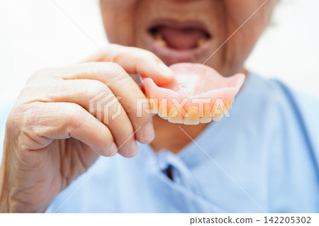 Doctor holding teeth denture in hand for dentist studying about dentistry. Doctor holding teeth denture in hand for dentist studying about dentistry. 142205302