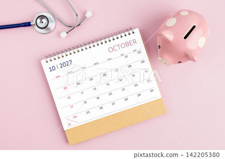 October 2027 desk calendar and stethoscope with piggy bank, Savings for Health insurance concept. October 2027 desk calendar and stethoscope with piggy bank, Savings for Health insurance concept. 142205380