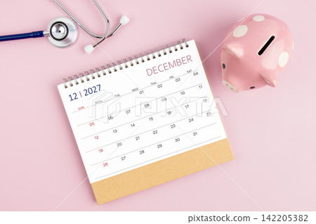 December 2027 desk calendar and stethoscope with piggy bank, Savings for Health insurance concept. December 2027 desk calendar and stethoscope with piggy bank, Savings for Health insurance concept. 142205382