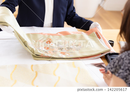 On-site purchase: The hands of an appraiser appraising kimonos at the customer's location. On-site purchase: The hands of an appraiser appraising kimonos at the customer's location. 142205617