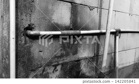Black and white PVC water pipes installed on a concrete block wall. 142205841