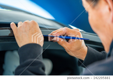 A car wrapping specialist applies a polyurethane film to the car. Detailer PPF 142205881