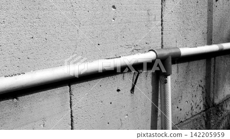 Horizontal PVC water pipe with a T-fitting on a concrete block wall. Horizontal PVC water pipe with a T-fitting on a concrete block wall. 142205959