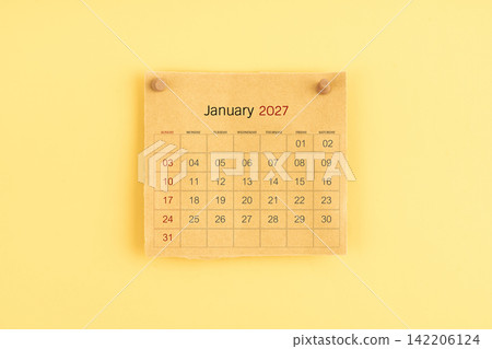 January 2027 brown calendar with wooden thumbtack on yellow background. January 2027 brown calendar with wooden thumbtack on yellow background. 142206124