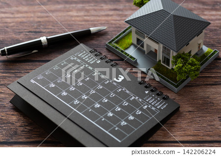 A black calendar for March and a model house. A black calendar for March and a model house. 142206224