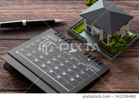 A black calendar for July and a model house. A black calendar for July and a model house. 142206460