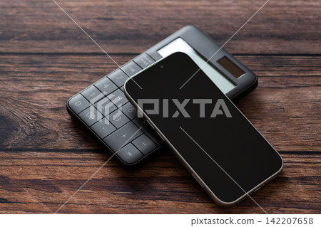 一台黑色計算器和一部智慧型手機 一台黑色計算器和一部智慧型手機 142207658