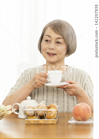 一位老婦人在客廳吃早餐麵包。 一位老婦人在客廳吃早餐麵包。 142207938