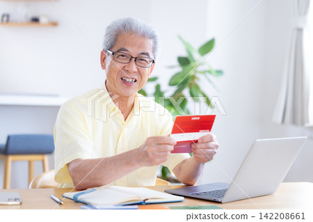 一位老人在客廳看著他的銀行存摺。 一位老人在客廳看著他的銀行存摺。 142208661