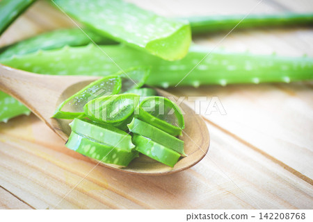 aloe vera plant slice on wood table background / close up of fresh aloe vera leaf with gel natural herbs and herbal medicines 142208768