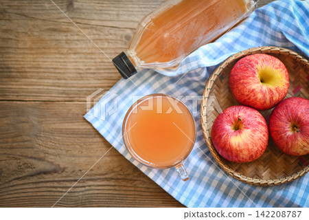 apple cider vinegar natural remedies and cures for common health condition, raw and unfiltered organic apple cider vinegar in glass with apple fruit on the wooden table 142208787