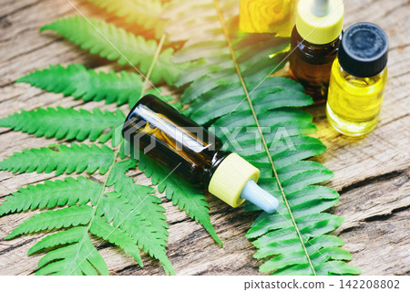 Aromatherapy herbal oil bottles aroma with fern leaves herbal formulations including wildflowers and herbs on wood - Essential oils natural on wooden and green leaf organic 142208802