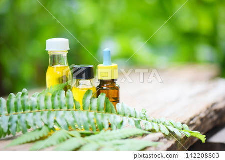 Aromatherapy herbal oil bottles aroma with fern leaves herbal formulations including wildflowers and herbs on wood - Essential oils natural on wooden and green leaf organic Aromatherapy herbal oil bottles aroma with fern leaves herbal formulations including wildflowers and herbs on wood - Essential oils natural on wooden and green leaf organic 142208803