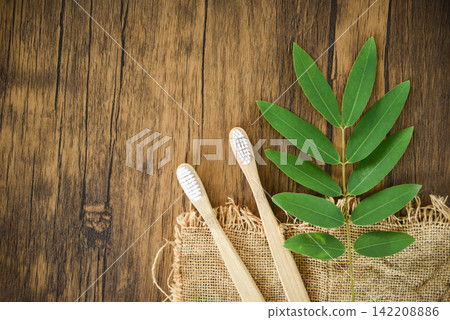 bamboo toothbrush and green leaf on rustic background - Zero waste Bathroom use less plastic concept bamboo toothbrush and green leaf on rustic background - Zero waste Bathroom use less plastic concept 142208886
