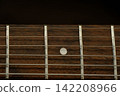 Guitar strings on a wooden fingerboard. 142208966