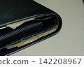 A wallet with money sticking out. 142208967