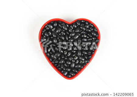 Black beans in red heart plate / black bean seed cereal whole grains isolated on white background Black beans in red heart plate / black bean seed cereal whole grains isolated on white background 142209065