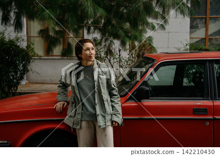 Woman stands near red car in urban area during daylight today Woman stands near red car in urban area during daylight today 142210430