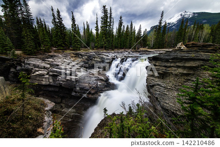 Waterfall in Rocky Mountain Forest Under Dramatic Cloudy Sky Waterfall in Rocky Mountain Forest Under Dramatic Cloudy Sky 142210486
