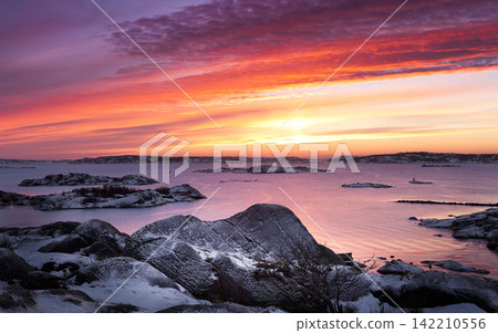 Winter Coastal Sunset Over Snowy Rocky Islands and Calm Sea Winter Coastal Sunset Over Snowy Rocky Islands and Calm Sea 142210556