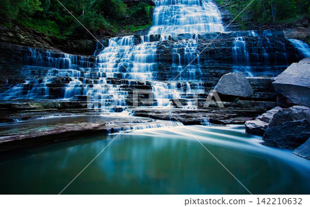 Waterfall Cascading Over Rocky Forest Ledges in Long Exposure Waterfall Cascading Over Rocky Forest Ledges in Long Exposure 142210632