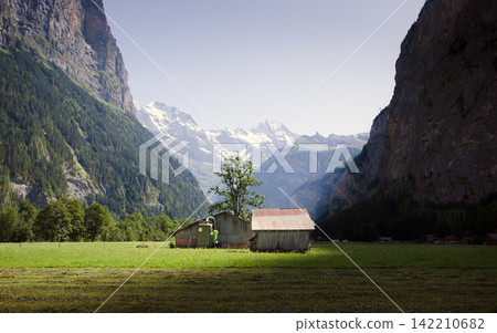 Alpine Valley Meadow with Rustic Barns and Snowy Mountain Peaks Alpine Valley Meadow with Rustic Barns and Snowy Mountain Peaks 142210682