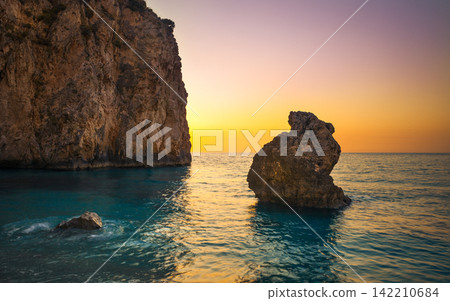 Sunset Seascape with Rocky Cliffs and Calm Ocean Water Sunset Seascape with Rocky Cliffs and Calm Ocean Water 142210684
