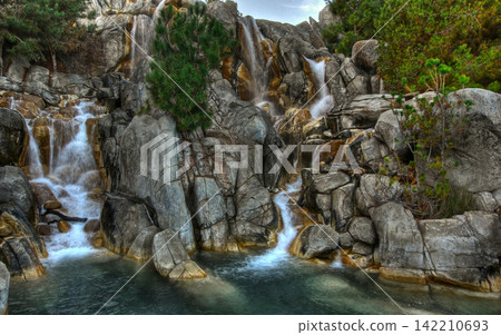 Waterfall Landscape with Rocky Cliffs and Pine Trees 142210693