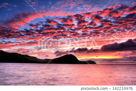 Sunset Seascape with Dramatic Pink Clouds and Mountain Silhouette Sunset Seascape with Dramatic Pink Clouds and Mountain Silhouette 142210976