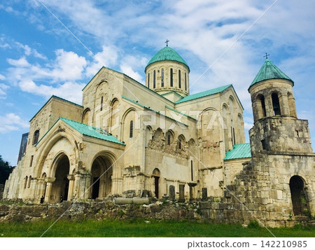 Historic Stone Cathedral with Green Domes Under Blue Sky 142210985