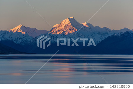 Snowy Mountain Range at Sunset Reflected in Calm Lake Snowy Mountain Range at Sunset Reflected in Calm Lake 142210990