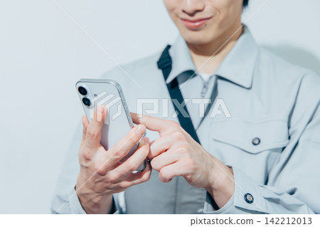 一名身穿工作服的男子正在操作他的智慧型手機。 一名身穿工作服的男子正在操作他的智慧型手機。 142212013