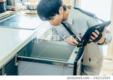 一位穿著工作服的男性商人診斷、檢查和評估廚房裡的洗碗機和洗碗機。 一位穿著工作服的男性商人診斷、檢查和評估廚房裡的洗碗機和洗碗機。 142212035