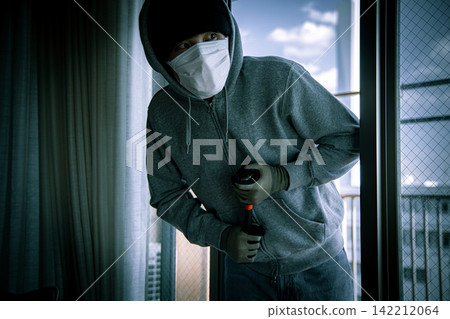 A young male intruder attempting to enter through a window. A young male intruder attempting to enter through a window. 142212064