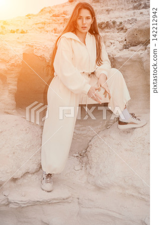 Woman canyon fashion sitting on white rock formations in a sunny desert landscape during golden hour Woman canyon fashion sitting on white rock formations in a sunny desert landscape during golden hour 142212942