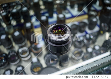 Camera lens at the center of a photography store display surrounded by out-of-focus lenses in a grid pattern Camera lens at the center of a photography store display surrounded by out-of-focus lenses in a grid pattern 142213137