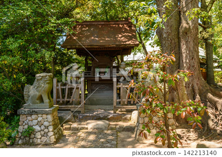 A serene traditional Japanese shrine nestled within a lush garden, surrounded by stone guardian lions A serene traditional Japanese shrine nestled within a lush garden, surrounded by stone guardian lions 142213140
