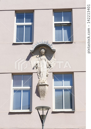 A relief sculpture of the Virgin Mary is centrally located on the facade of a building A relief sculpture of the Virgin Mary is centrally located on the facade of a building 142213401