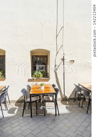 An outdoor seating area features wooden tables and chairs set in a street of Brno, Czech Republic An outdoor seating area features wooden tables and chairs set in a street of Brno, Czech Republic 142213404