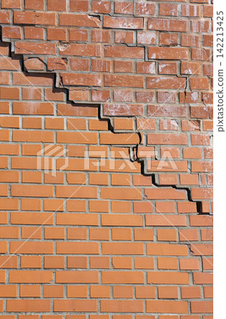 A large crack runs diagonally across a brick wall. A large crack runs diagonally across a brick wall. 142213425